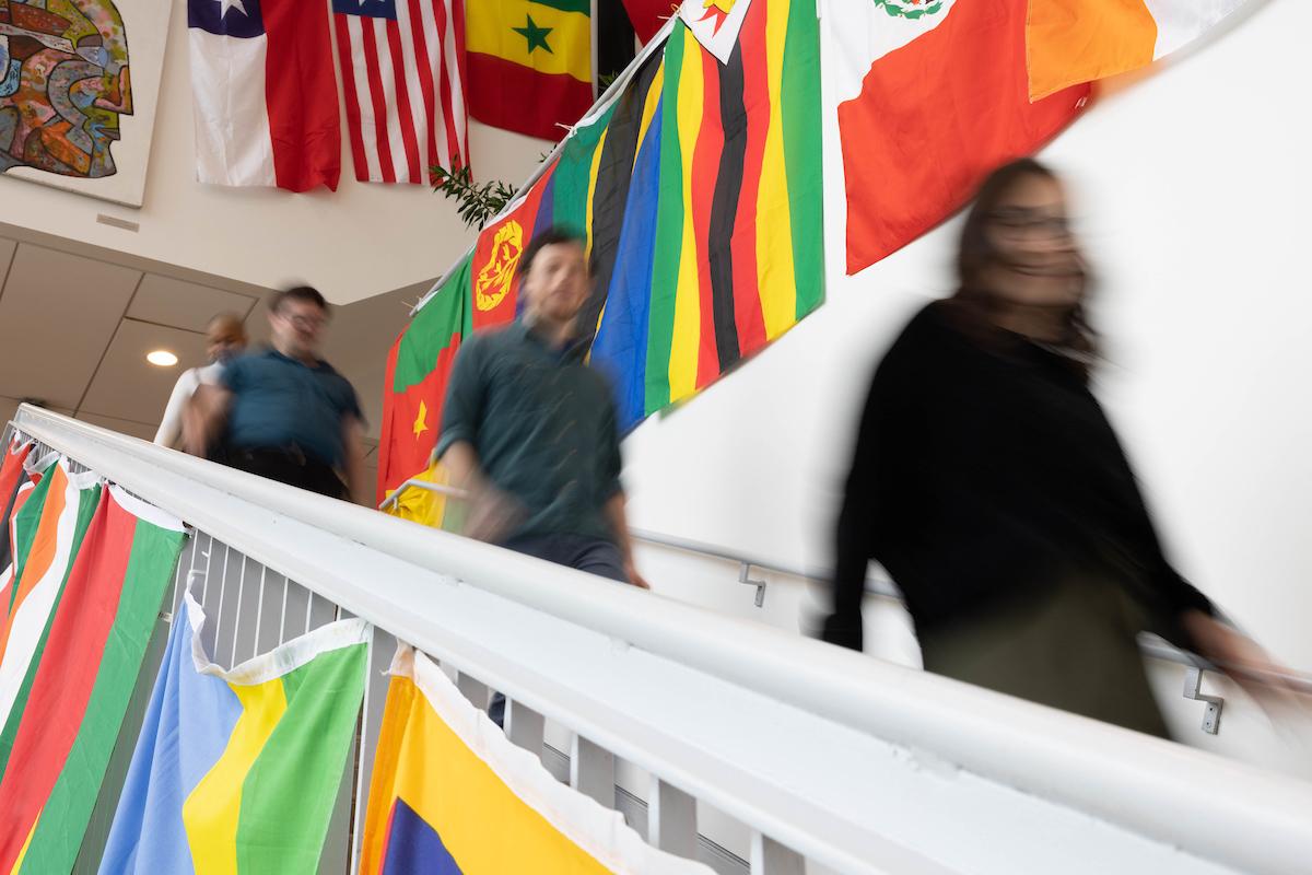 三个迷糊的学生走下楼梯，走过许多国家的国旗.
