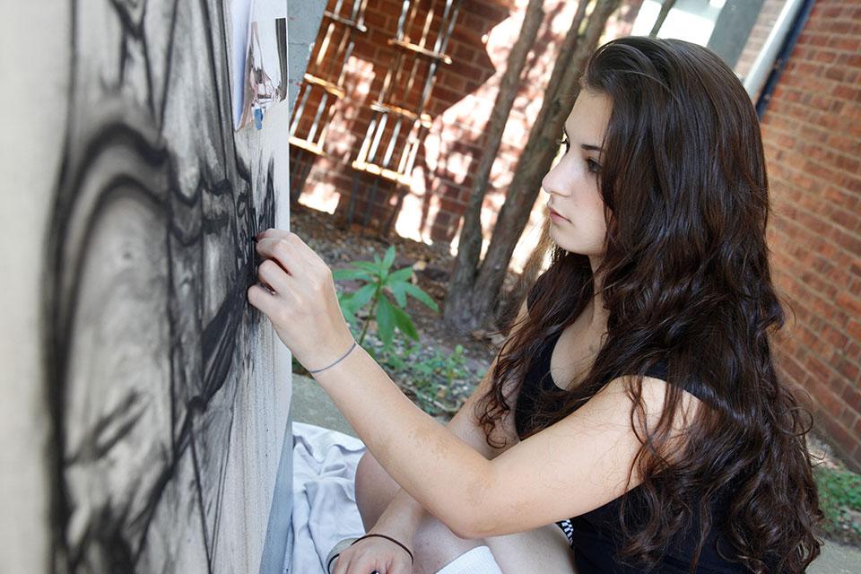 Student creating a work of art using charcoal